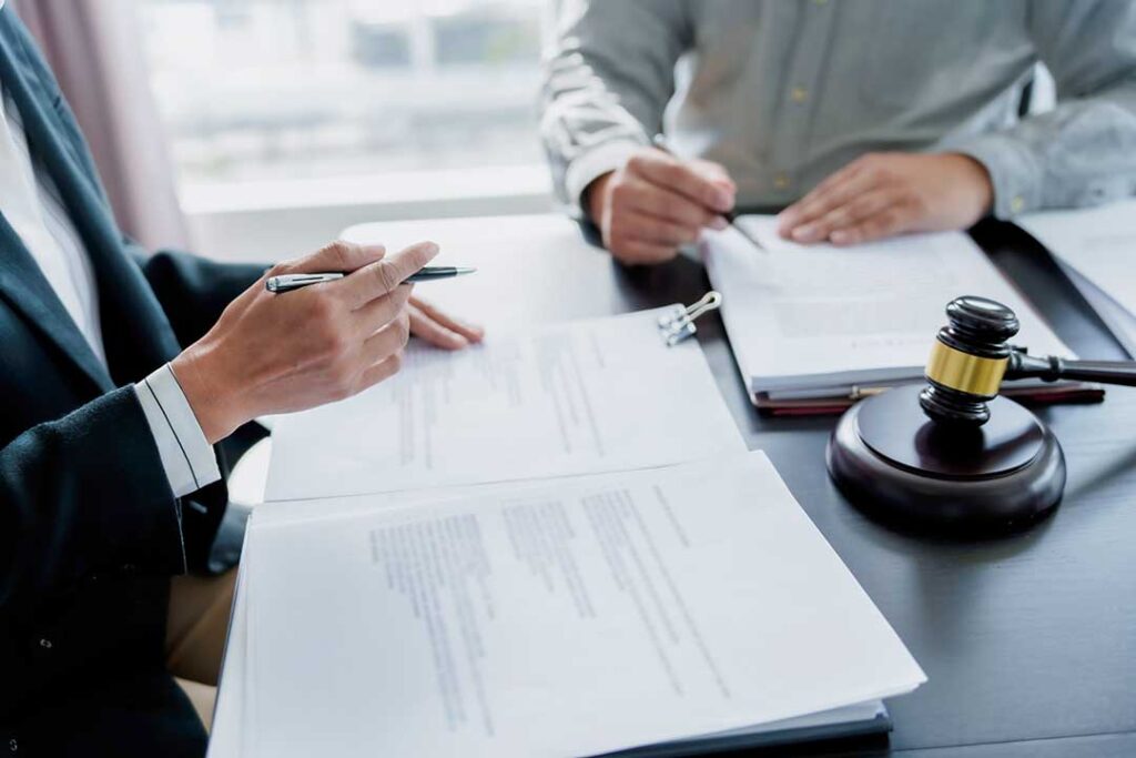 A person sits at a desk organizing paperwork and taking notes in preparation for a meeting.