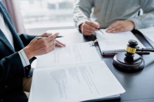 A person sits at a desk organizing paperwork and taking notes in preparation for a meeting.
