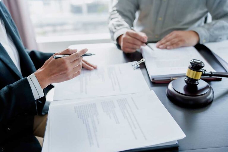 A person sits at a desk organizing paperwork and taking notes in preparation for a meeting.